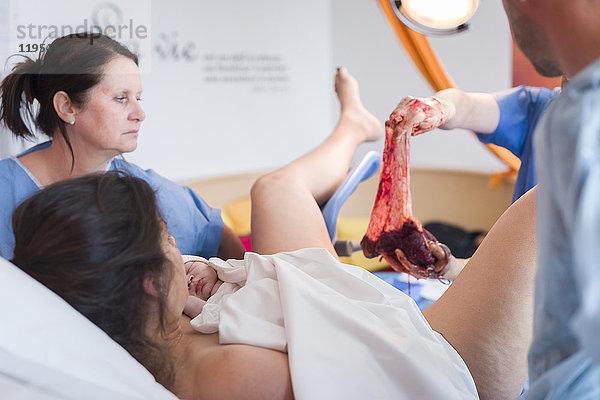 Reportage über Maureen während ihrer zweiten Schwangerschaft. Vaginale Geburt in der Klinik Santa Maria in Nizza  Frankreich. Der Arzt entfernt die Plazenta.