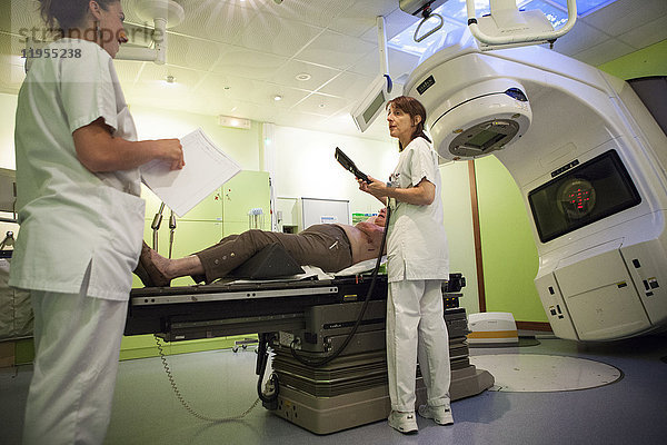 Reportage aus der Strahlentherapieabteilung eines Krankenhauses in Savoie  Frankreich. Zwei Techniker bereiten eine Patientin für eine Strahlentherapie zur Behandlung von Brustkrebs vor.
