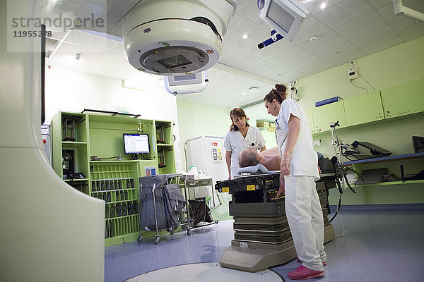 Reportage in der Strahlentherapieabteilung eines Krankenhauses in Savoie  Frankreich. Zwei Techniker bereiten einen Patienten für eine Strahlentherapie zur Behandlung eines Adenokarzinoms der Hals- und Rückenwirbelsäule vor.