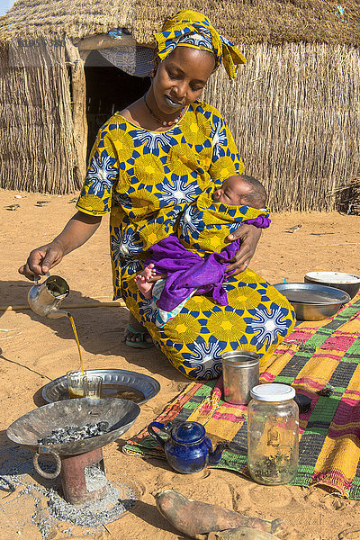 Junge Mutter schenkt Tee ein. Senegal.
