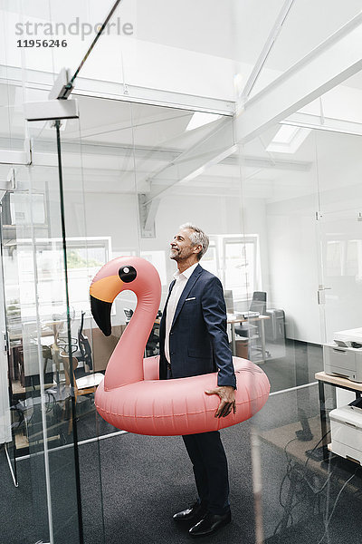 Geschäftsmann im Büro mit aufblasbarem Flamingo