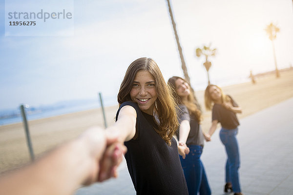 Fröhliche junge Frauen halten ihre Hände im Freien.