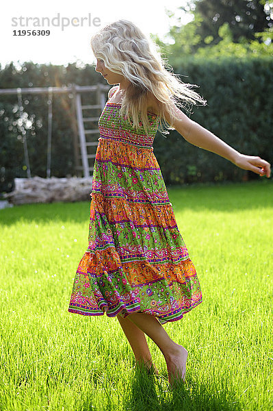 Mädchen im Kleid beim Spielen im Garten