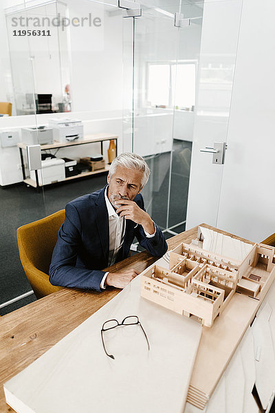 Ausgereifter Geschäftsmann mit Architekturmodell im Büro