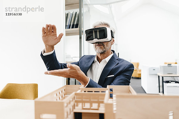 Ausgereifter Geschäftsmann mit Architekturmodell im Büro mit VR-Brille