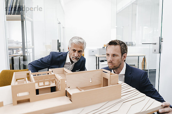 Zwei Geschäftsleute prüfen Architekturmodell im Büro