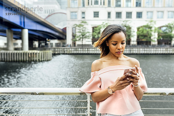 Frau sendet Nachrichten mit ihrem Smartphone in der Stadt