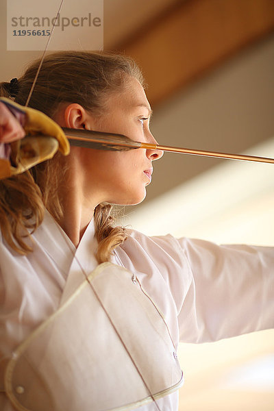 Kaukasische Frau übt traditionelles japanisches Kyudo-Bogenschießen