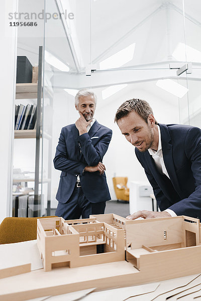 Zwei Geschäftsleute prüfen Architekturmodell im Büro