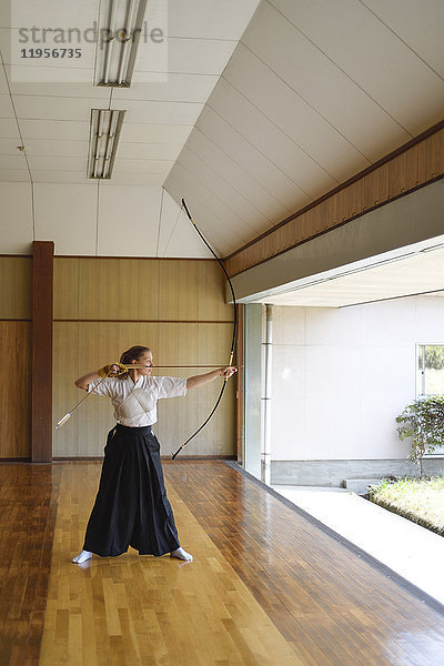 Kaukasische Frau übt traditionelles japanisches Kyudo-Bogenschießen