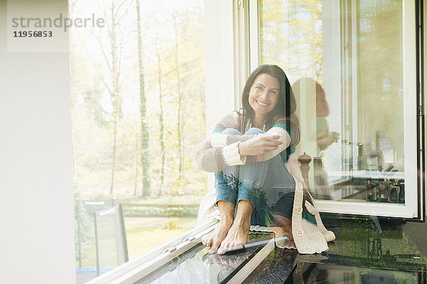 Porträt der lächelnden Frau zu Hause auf der Fensterbank
