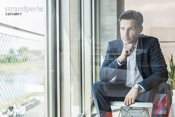 Porträt eines nachdenklichen Geschäftsmannes mit Blick durchs Fenster