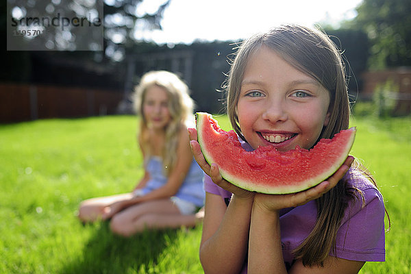 Glückliches Mädchen mit Wassermelone im Garten