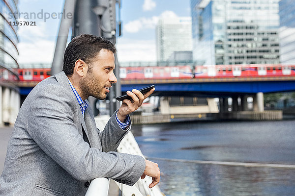 Geschäftsmann sendet Sprachnachrichten mit seinem Smartphone in der Stadt