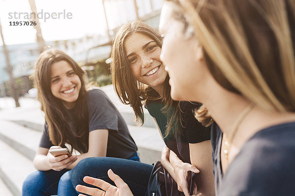 Drei glückliche junge Frauen sitzen im Freien