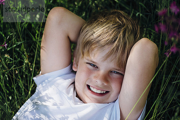 Porträt eines lächelnden kleinen Jungen auf der Wiese im Garten