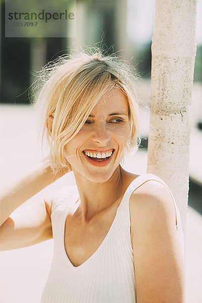 Porträt einer lachenden blonden Frau  die sich etwas ansieht