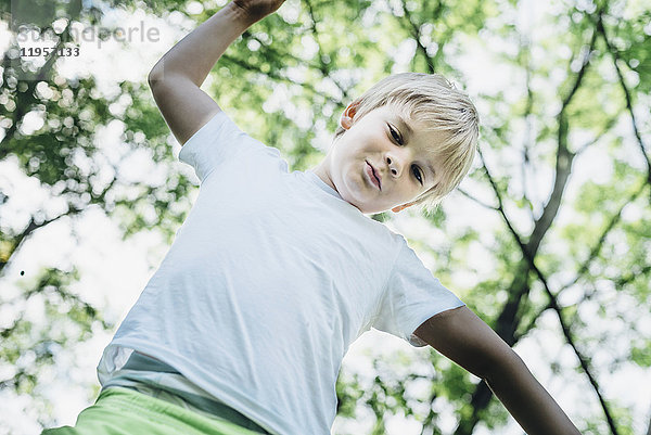 Porträt eines lächelnden kleinen Jungen  der auf einen Baum klettert.
