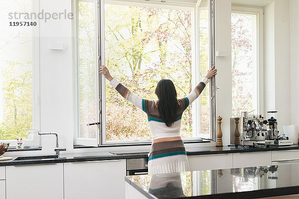 Frau in der Küche öffnet das Fenster