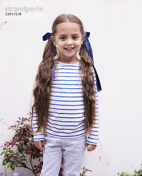 Porträt eines lächelnden kleinen Mädchens mit langen Zöpfen