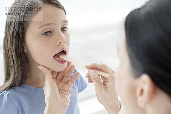 Eine Ärztin untersucht den Mund eines Mädchens.