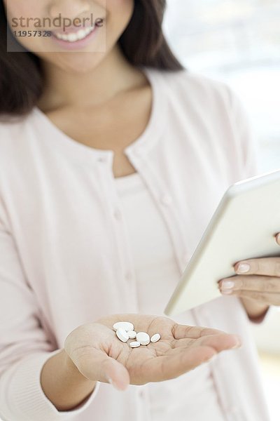 Junge Frau mit Pillen und digitalem Tablet.