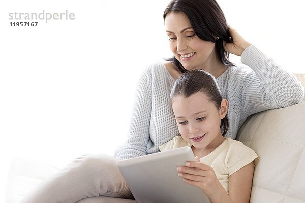 Mutter und Tochter auf dem Sofa mit digitalem Tablet.