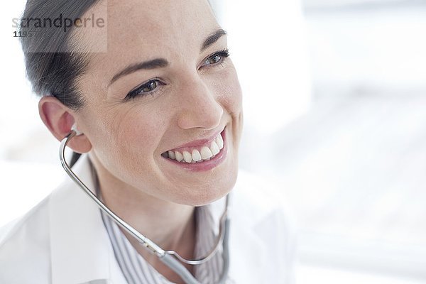 MODELL FREIGEGEBEN. Weiblicher Arzt mit Stethoskop  lächelnd.