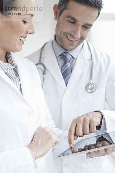 MODELL FREIGEGEBEN. Männliche und weibliche Ärzte mit digitalem Tablet.