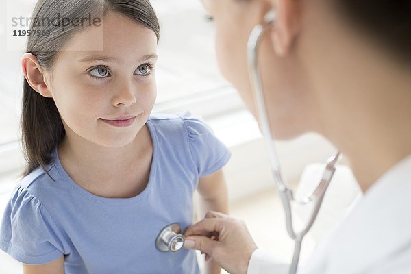Eine Ärztin hört die Brust eines Mädchens mit einem Stethoskop ab.