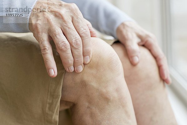 MODELL FREIGEGEBEN. Ältere Frau berührt Knie.