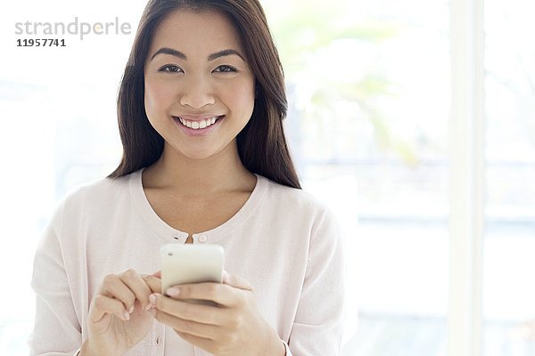 Junge Frau mit Smartphone  lächelnd.