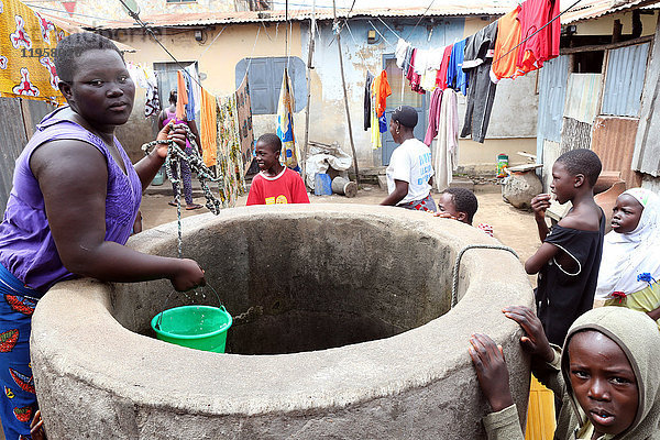 Eine Frau schöpft Wasser aus einem Brunnen  Lome  Togo  Westafrika  Afrika