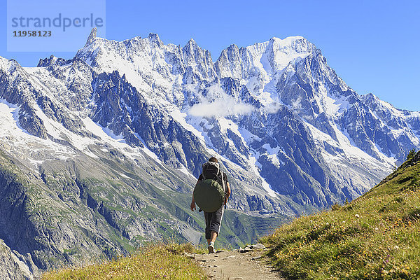 Wanderer läuft entlang des Weges mit Blick auf die Grandes Jorasses und den Riesenzahn  Venytal  Courmayeur  Aostatal  Italien  Europa