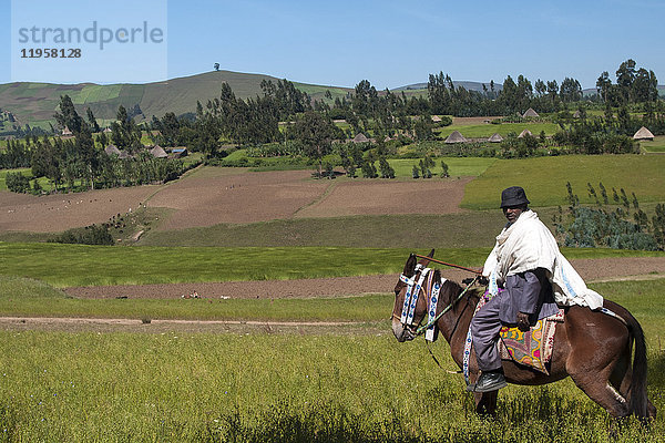 Ein Mann auf dem Pferderücken mit Blick auf die sanften Hügel des ländlichen Äthiopiens  Afrika