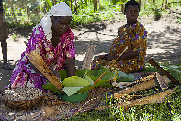 Eine Frau wickelt einige Erdnüsse in ein Bananenblatt  Uganda  Afrika