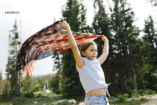 Mädchen (8-9) hält unsere Flagge im Wald