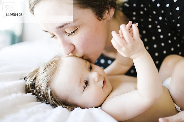 Baby-Mädchen (6-11 Monate) wird von der Mutter geküsst