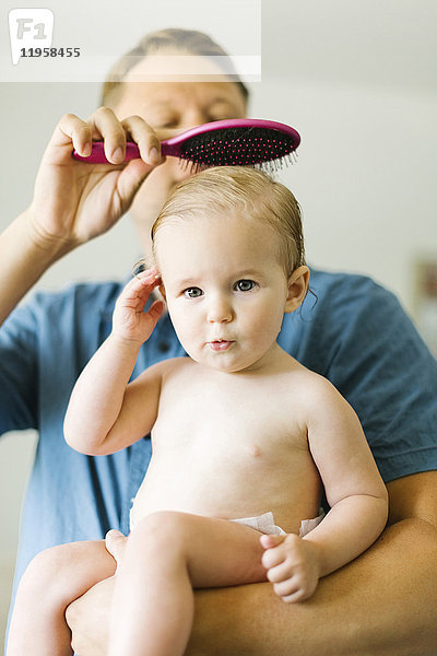 Vater und kleines Mädchen (12-17 Monate) beim Bürsten der Haare nach dem Bad