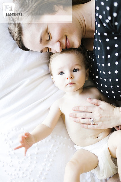 Baby-Mädchen (6-11 Monate)  das von seiner Mutter umarmt wird  direkt oben
