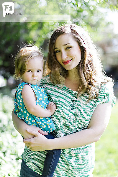 Porträt einer Mutter und eines kleinen Mädchens (12-17 Monate) im Hinterhof