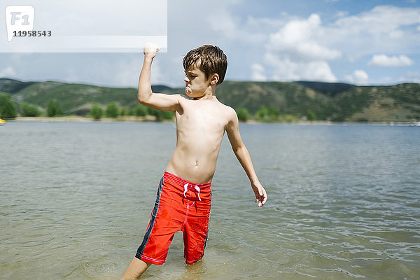USA  Utah  Park City  Junge (6-7) lässt beim Waten im See die Muskeln spielen