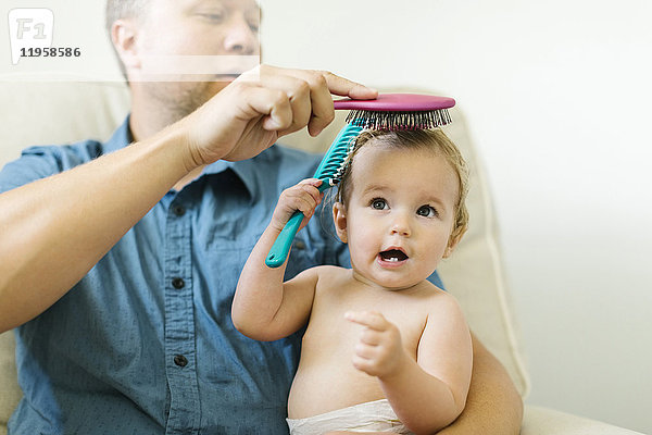 Vater und kleines Mädchen (12-17 Monate) beim Bürsten der Haare nach dem Bad