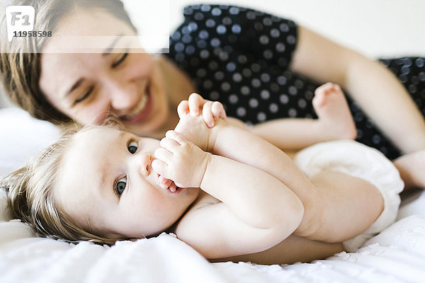 Baby Mädchen (6-11 Monate) beißt Fuß