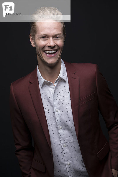 Porträt eines lachenden Mannes im kastanienbraunen Anzug
