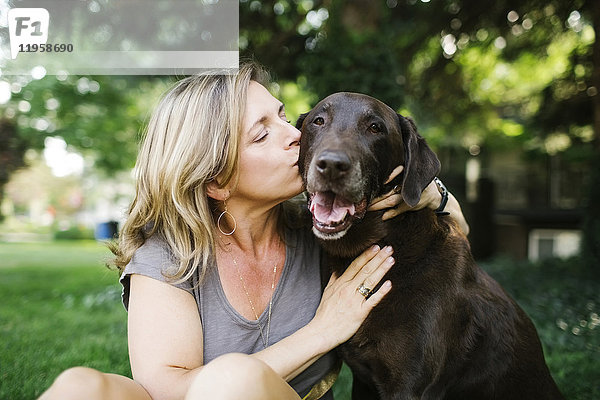Porträt einer Frau  die einen Labrador Retriever küsst