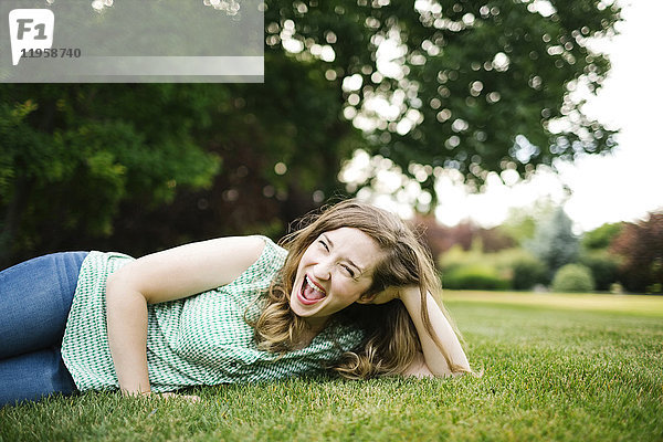 Porträt einer lachenden  im Gras liegenden Frau