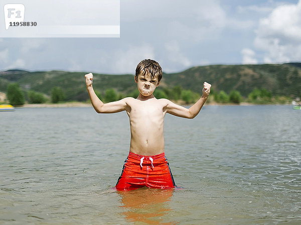 USA  Utah  Park City  Junge (6-7) lässt beim Waten im See die Muskeln spielen