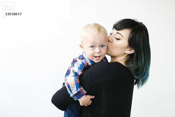 Porträt einer Mutter  die ihren Sohn (12-17 Monate) küsst  vor weißem Hintergrund