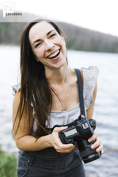 Porträt einer Frau mit Kamera am See